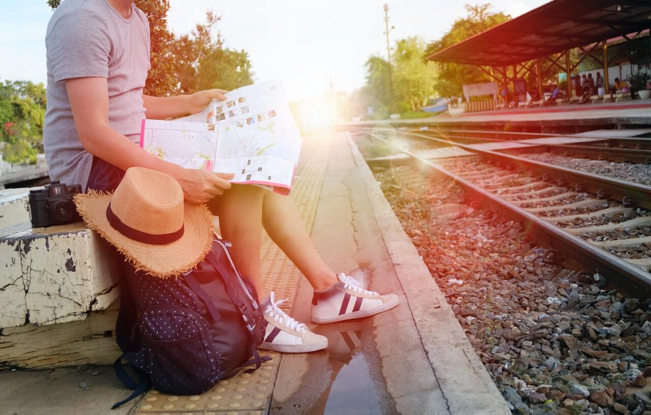 Image d'une femme attendant le train en tenant une carte